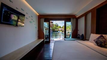 A hotel room with a large bed, a television mounted on the wall, and a view of an outdoor swimming pool.