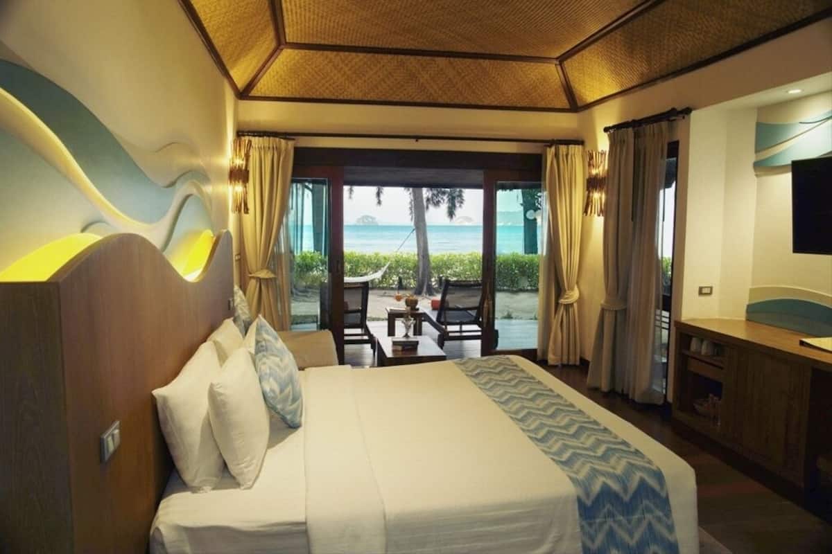 A hotel room with a bed, a desk, and a view of the ocean.