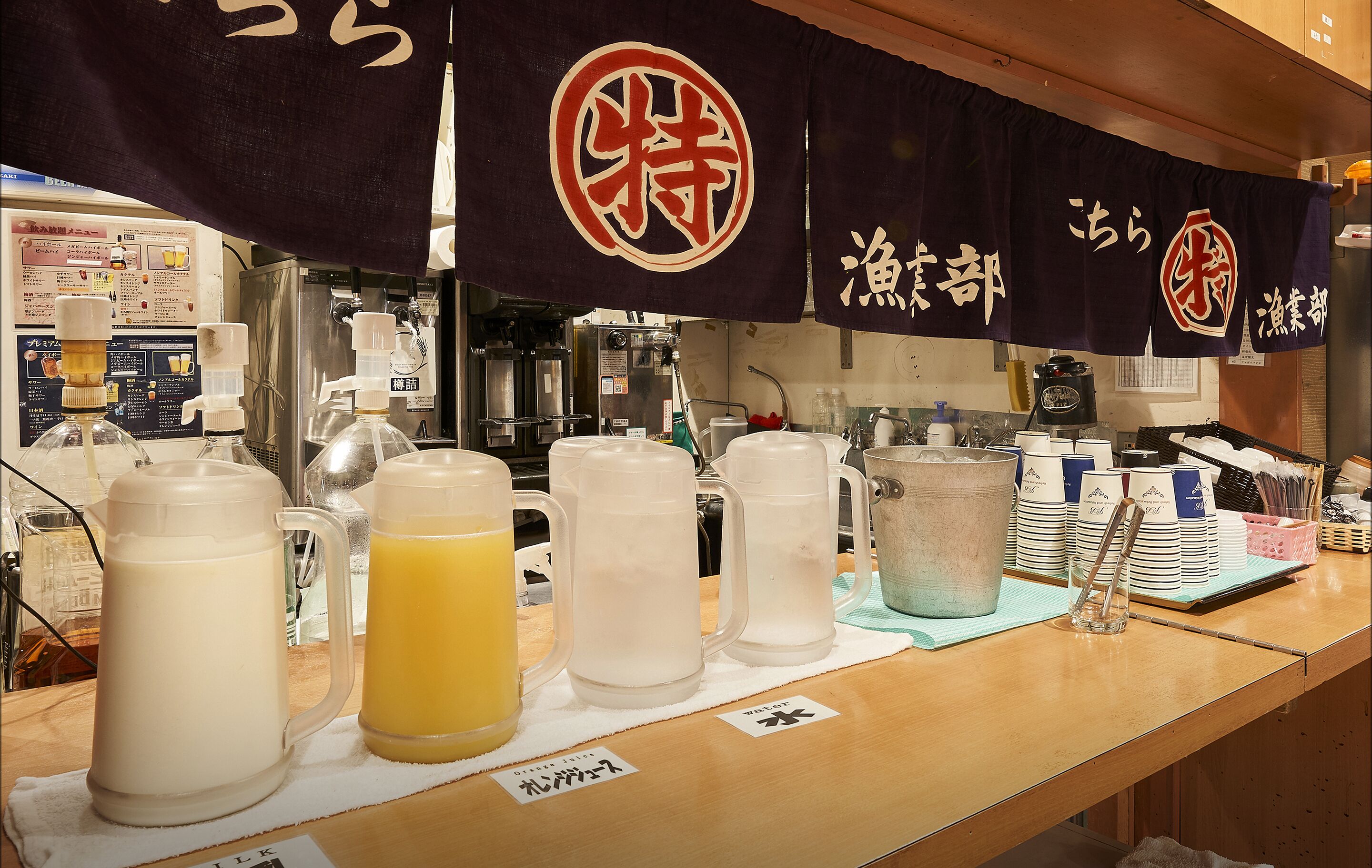A beverage station with various drinks and a menu board in the background.