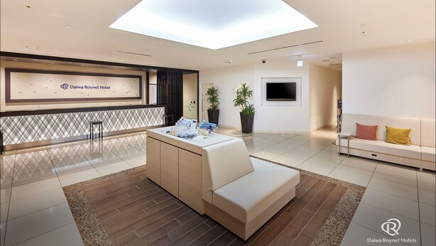 A modern hotel lobby with a reception desk, a seating area, a large TV, and a skylight. - Daiwa Roynet Hotel Sendai (Sendai)