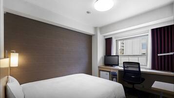 A hotel room with a bed, desk, chair, television, and a window with curtains.