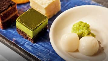 A dessert plate with various sweets, including a green square and two white round items, on a blue cloth.