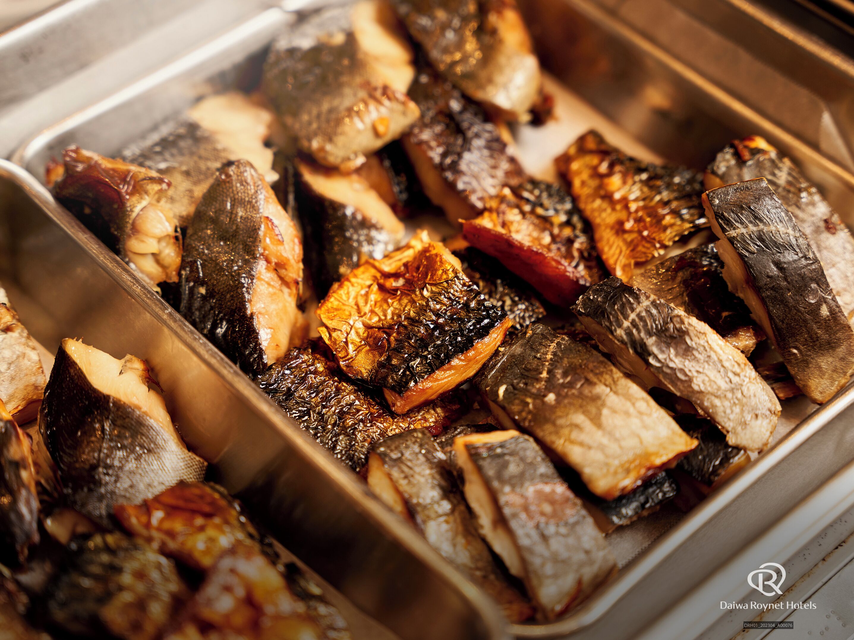A tray of cooked fish and vegetables.