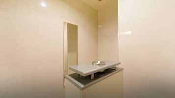 A modern bathroom with a white sink, mirror, and ventilation.
