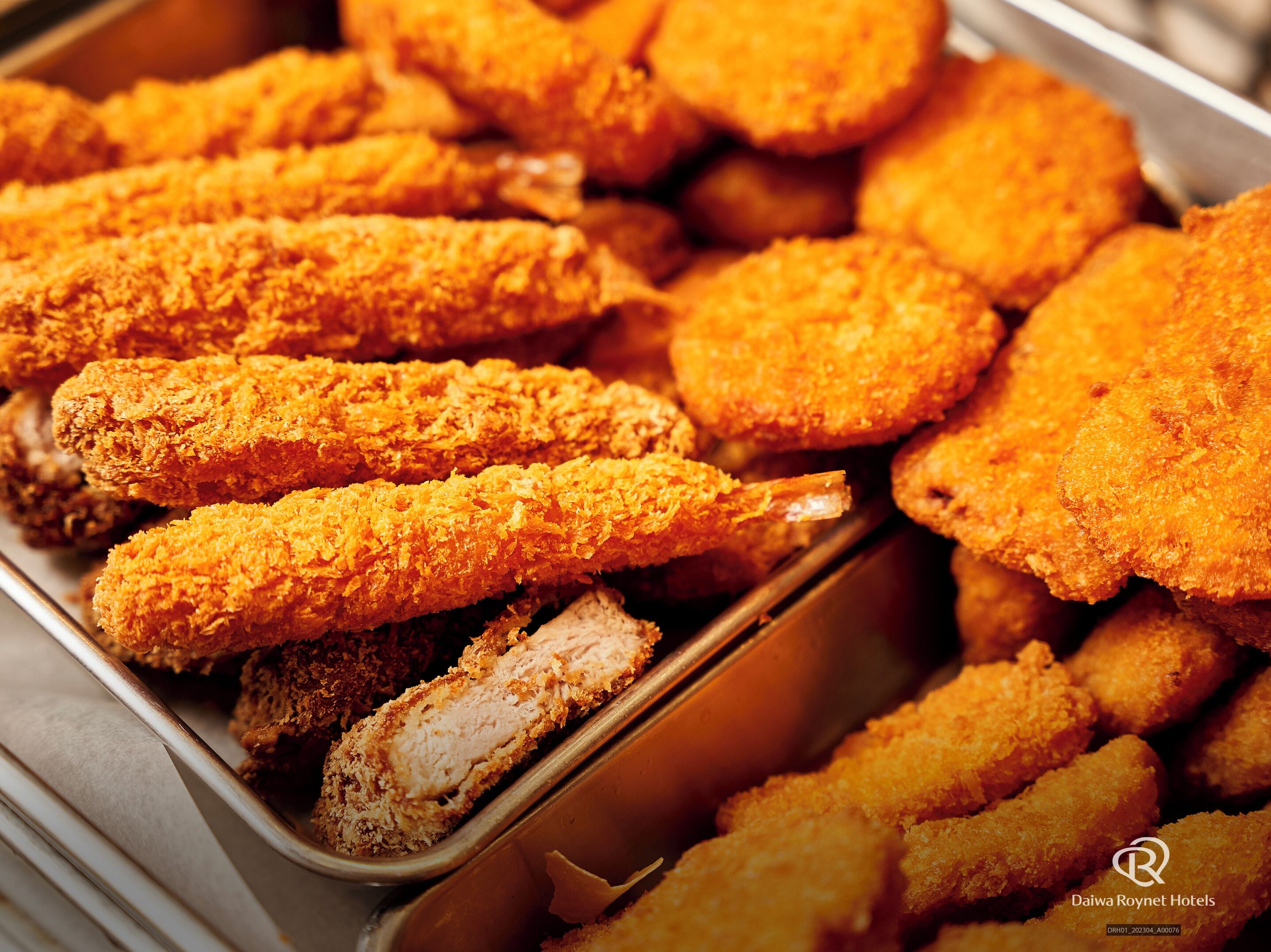 A tray of breaded and fried food items, likely a buffet selection.