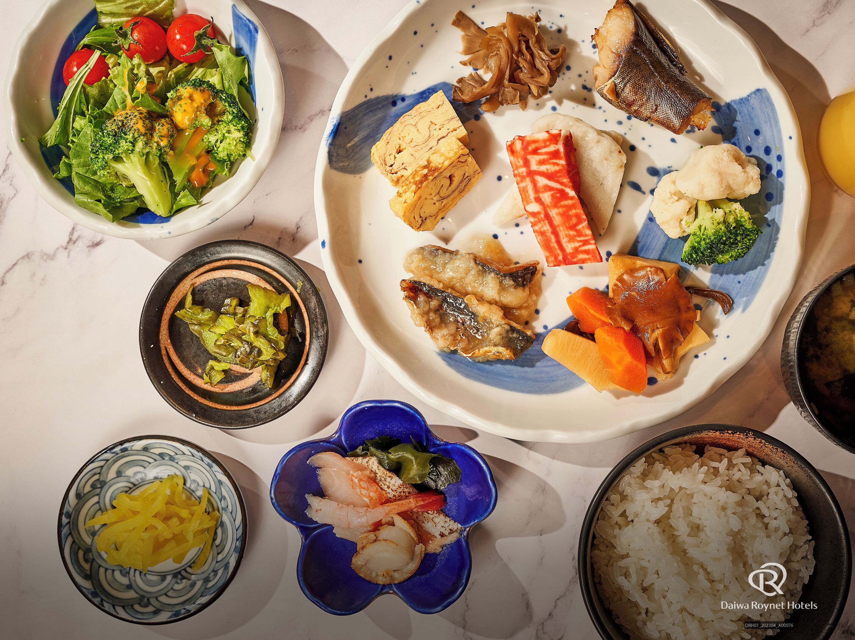 A variety of dishes including sushi, vegetables, and rice, suggesting a meal setting.