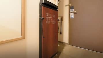 Un pasillo con una puerta de madera y un picaporte de metal, un cartel en la pared, y una puerta con lector de tarjeta de acceso.