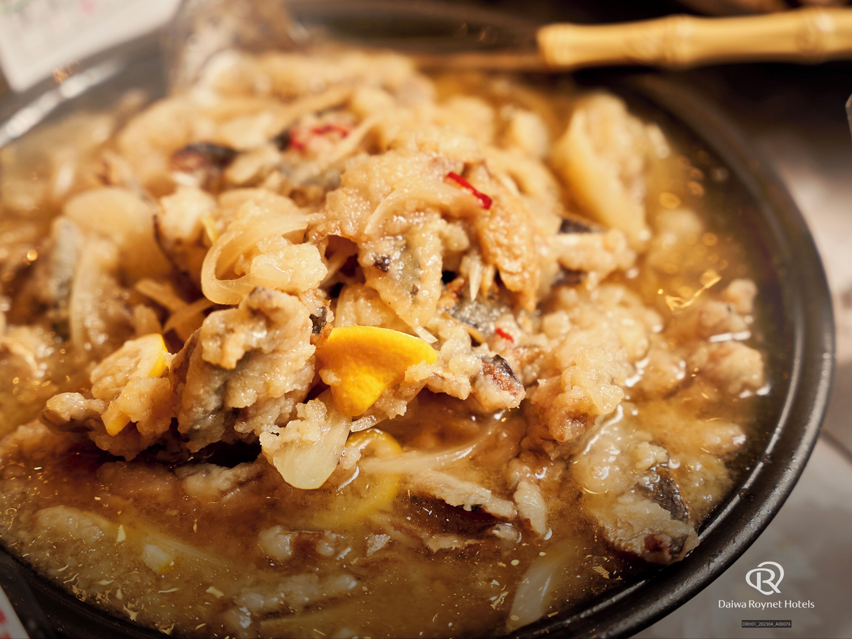 A close-up of a dish with various ingredients in a pan, possibly a stew or soup.