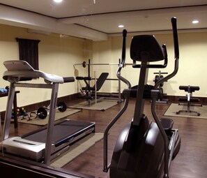 Une salle de sport équipée de tapis de course, de vélos elliptiques et de poids libres.