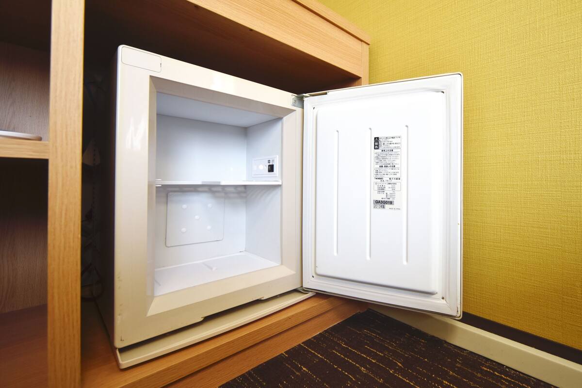 Ein offener Kühlschrank mit einem Aufkleber an der Tür, in einer Küche mit Holzausstattung und einer strukturierten Wand.
