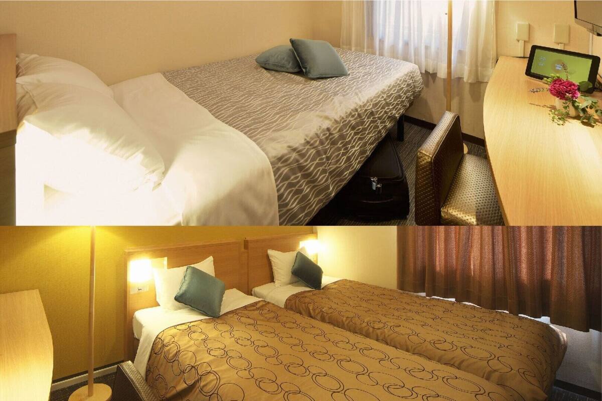 Ein Hotelzimmer mit Bett, Nachttisch und Schreibtisch mit Computer.