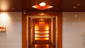 A hallway with a central illuminated display case, flanked by closed shuttered doors, leading to a reception area. - Yokohama Heiwa Plaza Hotel (Yokohama)