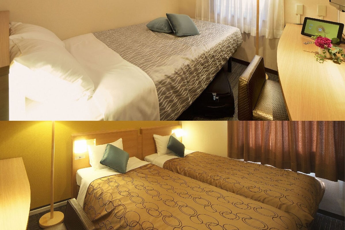 Ein Hotelzimmer mit Bett, Nachttisch und Schreibtisch mit Bildschirm.