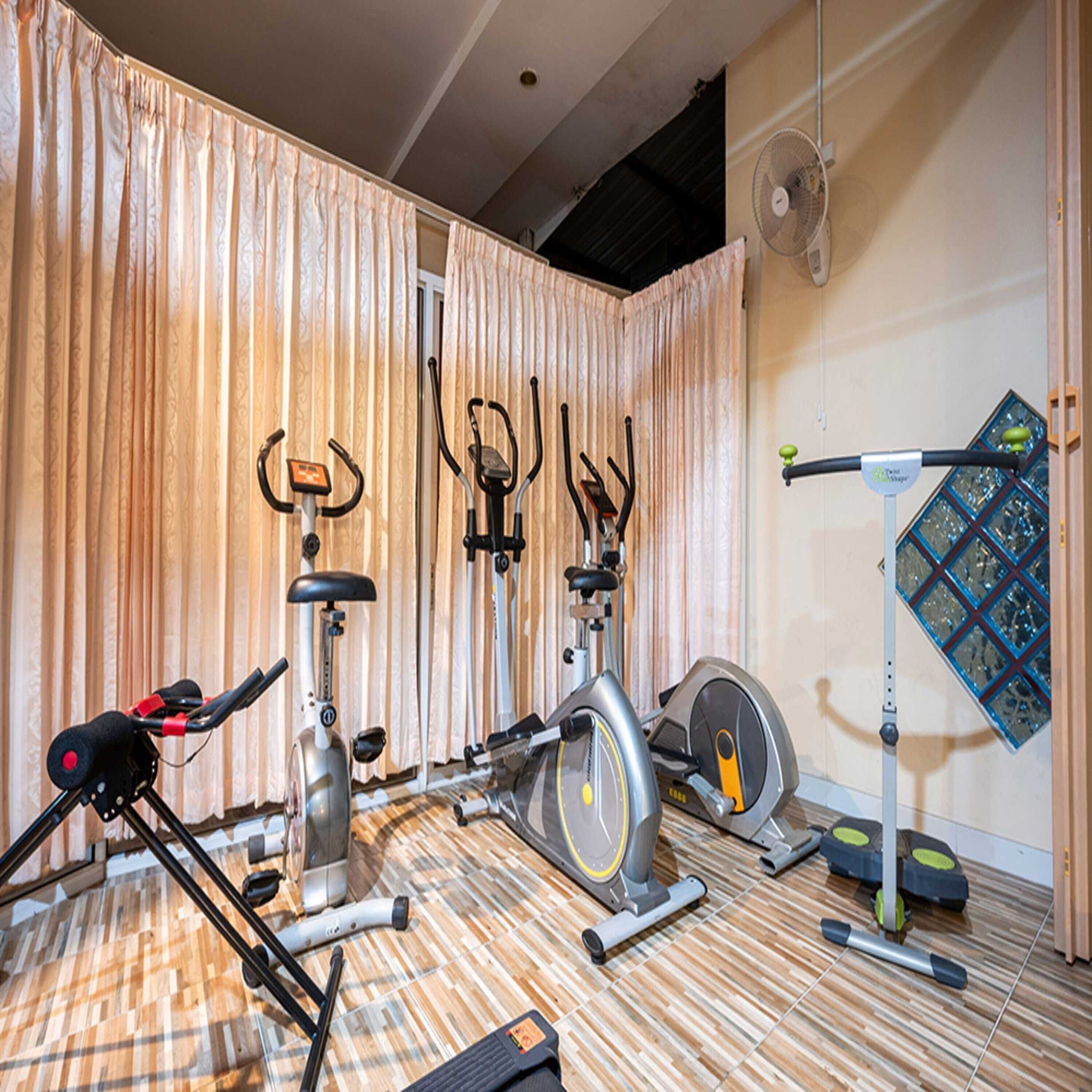 A home gym with various exercise equipment including an elliptical, stationary bike, and a treadmill.