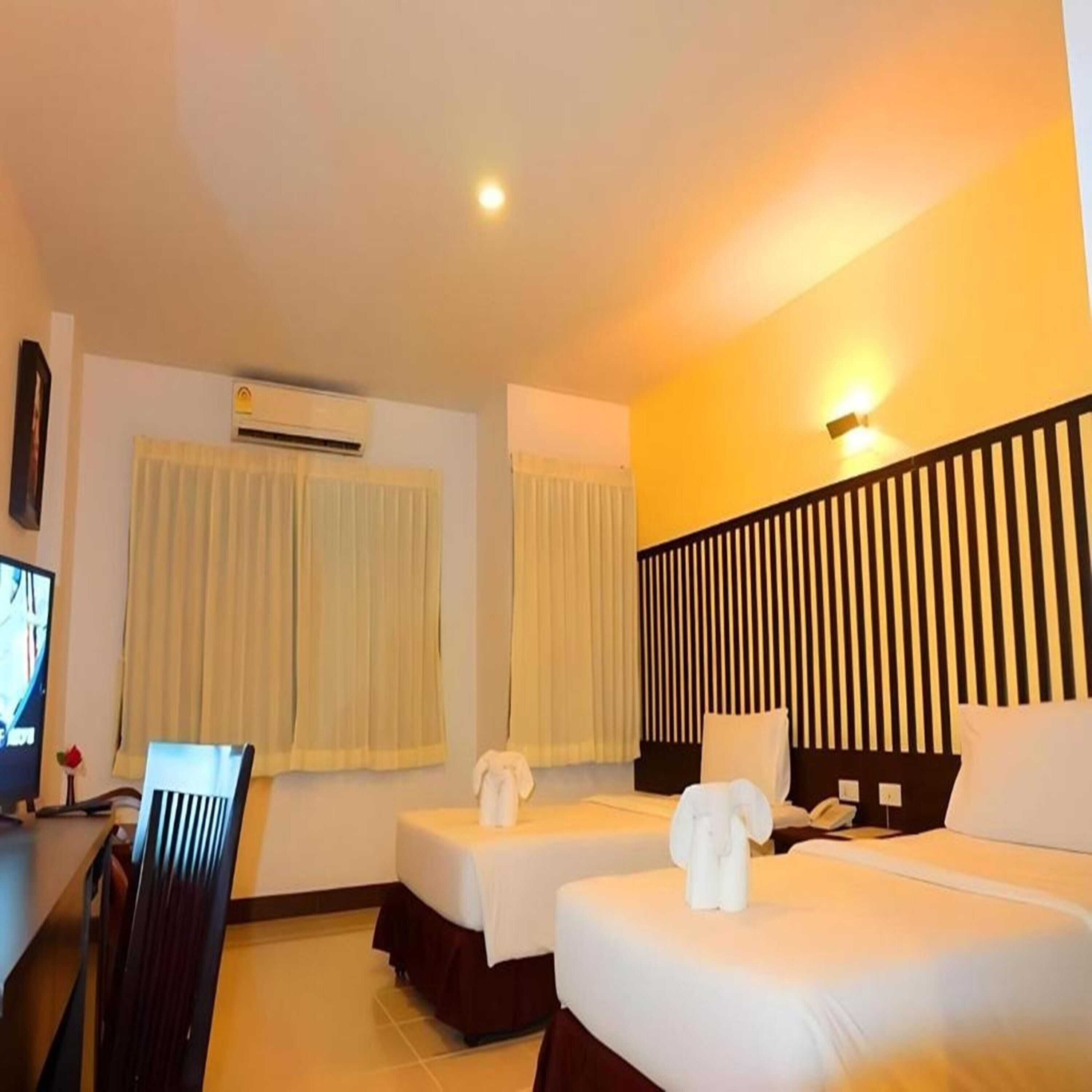 Une chambre d’hôtel avec deux lits, un bureau et une chaise.