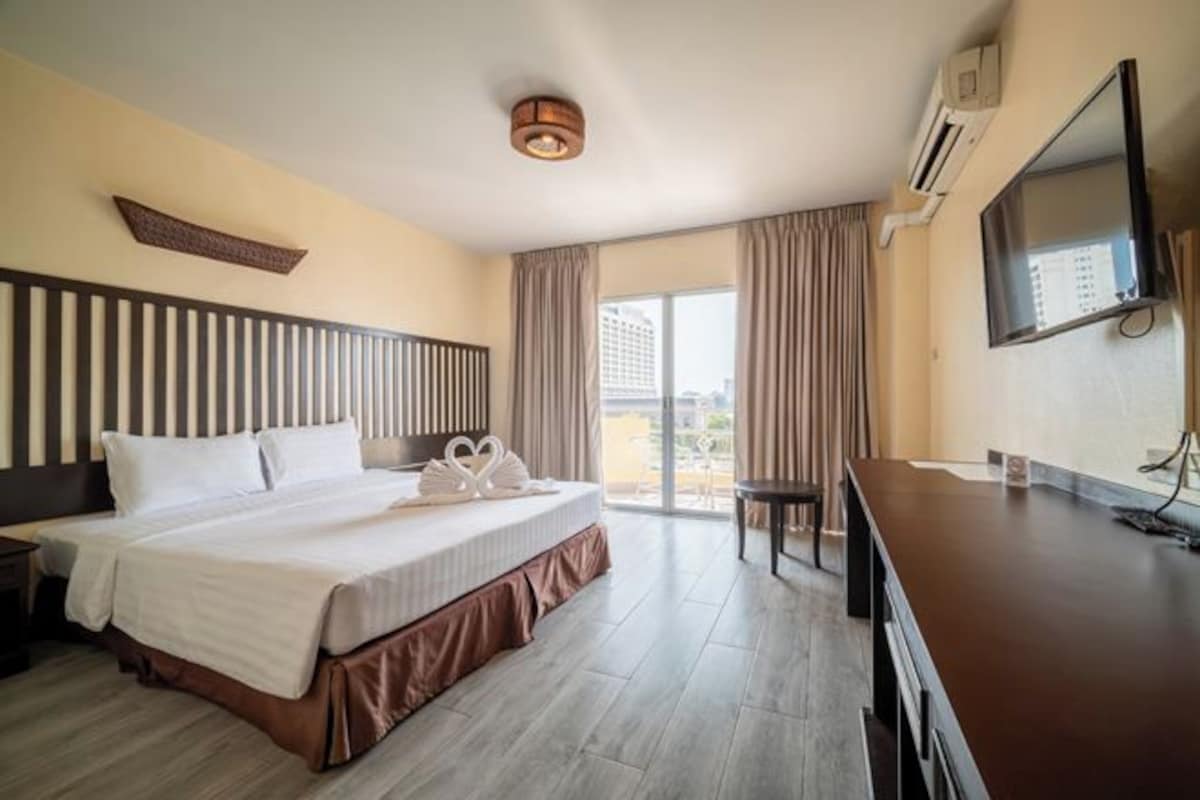 Habitación de hotel con una cama grande, un escritorio, un televisor y vistas a la ciudad.