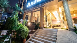 Un hôtel doté d’une façade moderne, de grandes fenêtres en verre et d’une enseigne indiquant « PLUS HOTEL ».
