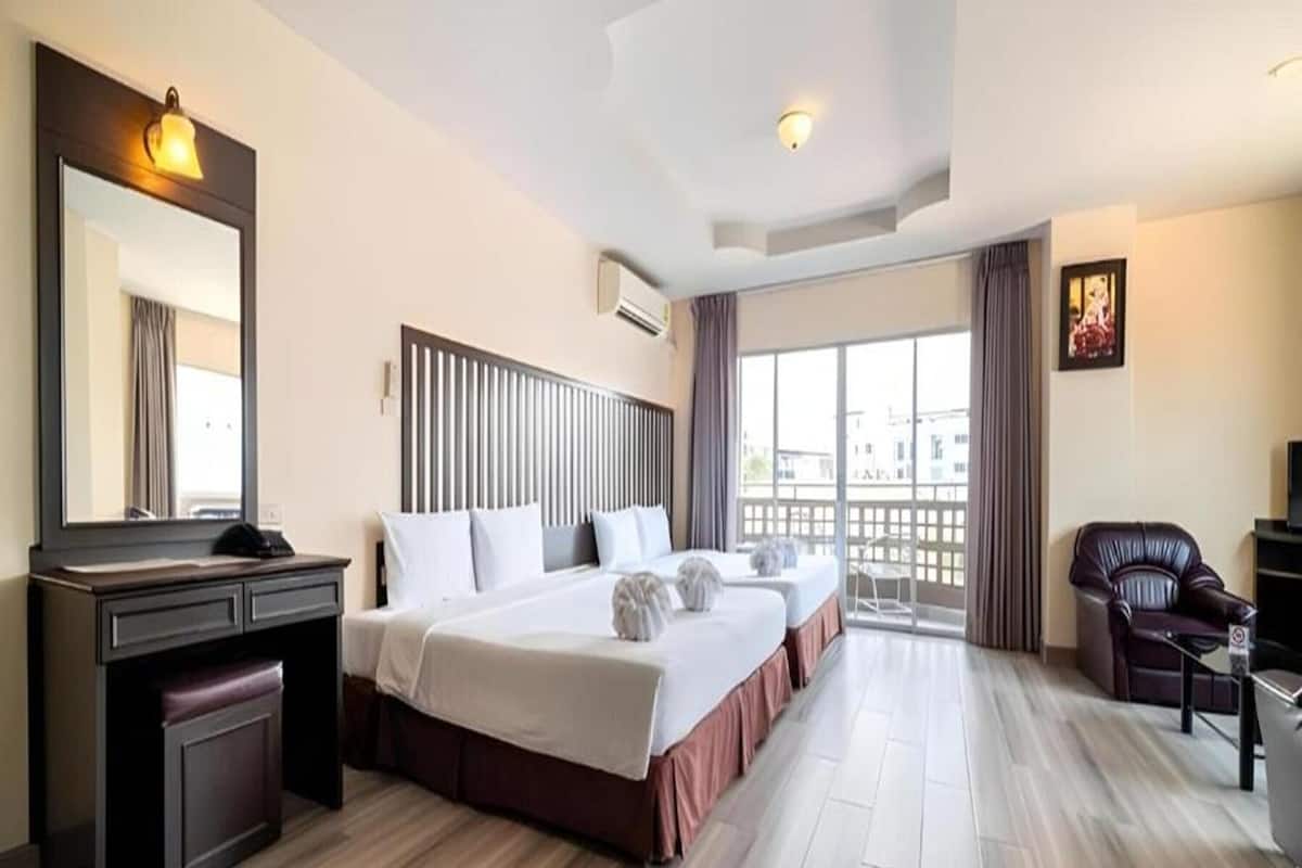 Een hotelkamer met een groot bed, een bureau, een stoel en een balkon met uitzicht.