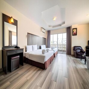 Habitación de hotel con una cama grande, un escritorio, una silla y un balcón con vistas.