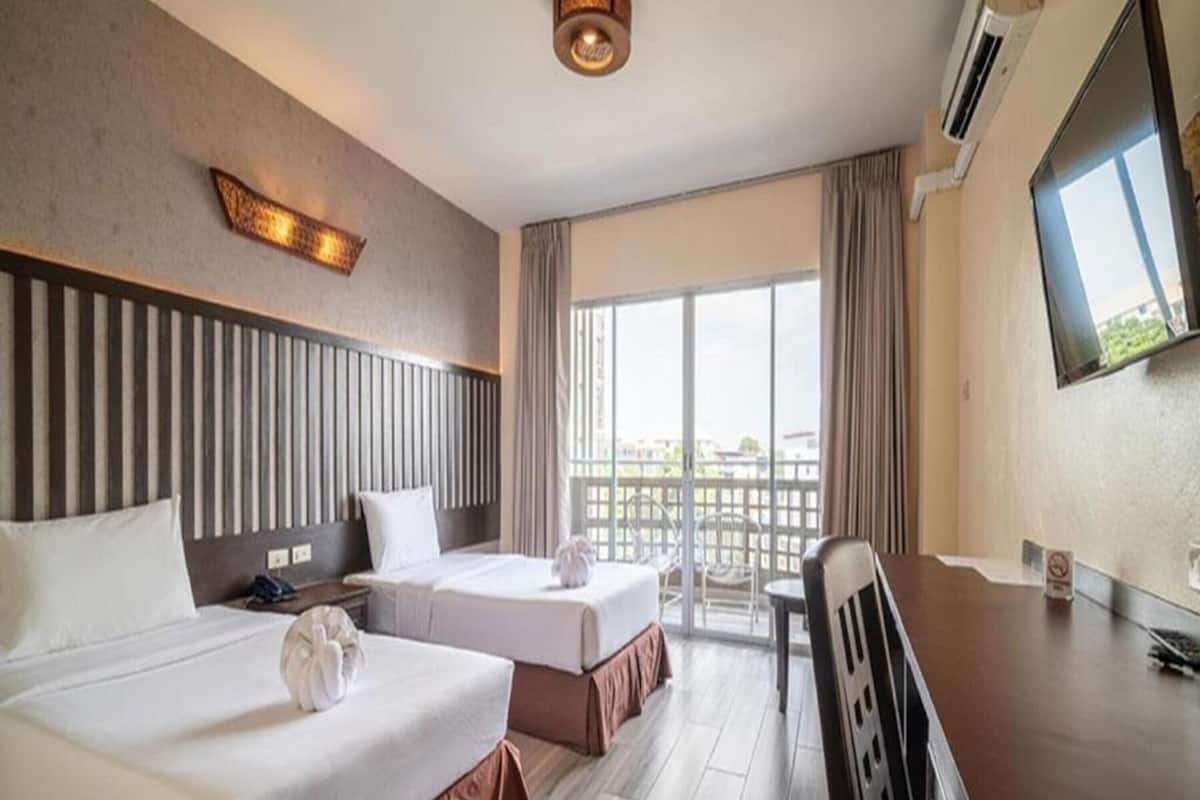 Een hotelkamer met twee bedden, een bureau, een stoel, een televisie en een balkon met uitzicht.