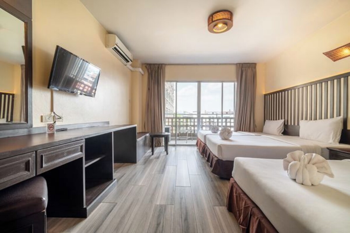 Een hotelkamer met twee bedden, een bureau, een televisie en een balkon met uitzicht.