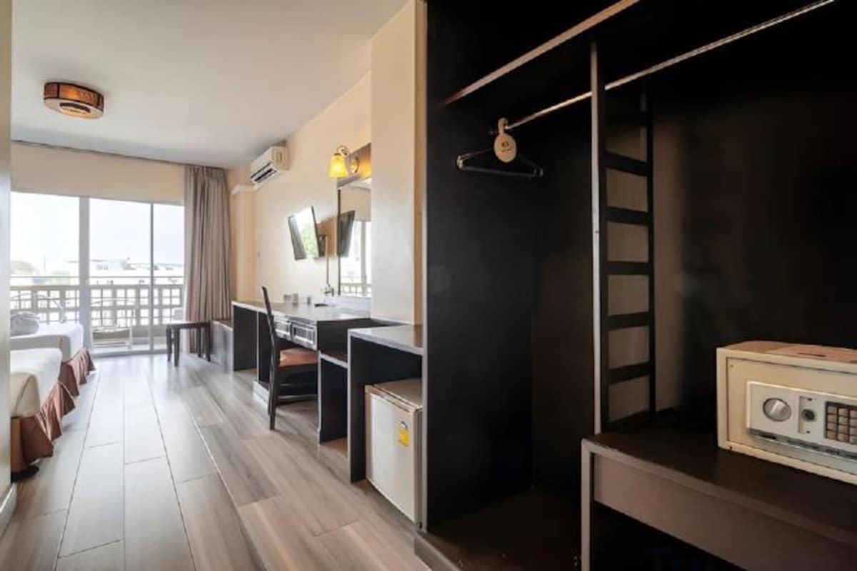 Una habitación de hotel con kitchenette, una cama, un escritorio y un ventanal grande.