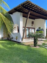 Un edificio moderno con un patio cubierto, un muro de piedra y un césped cuidado.
