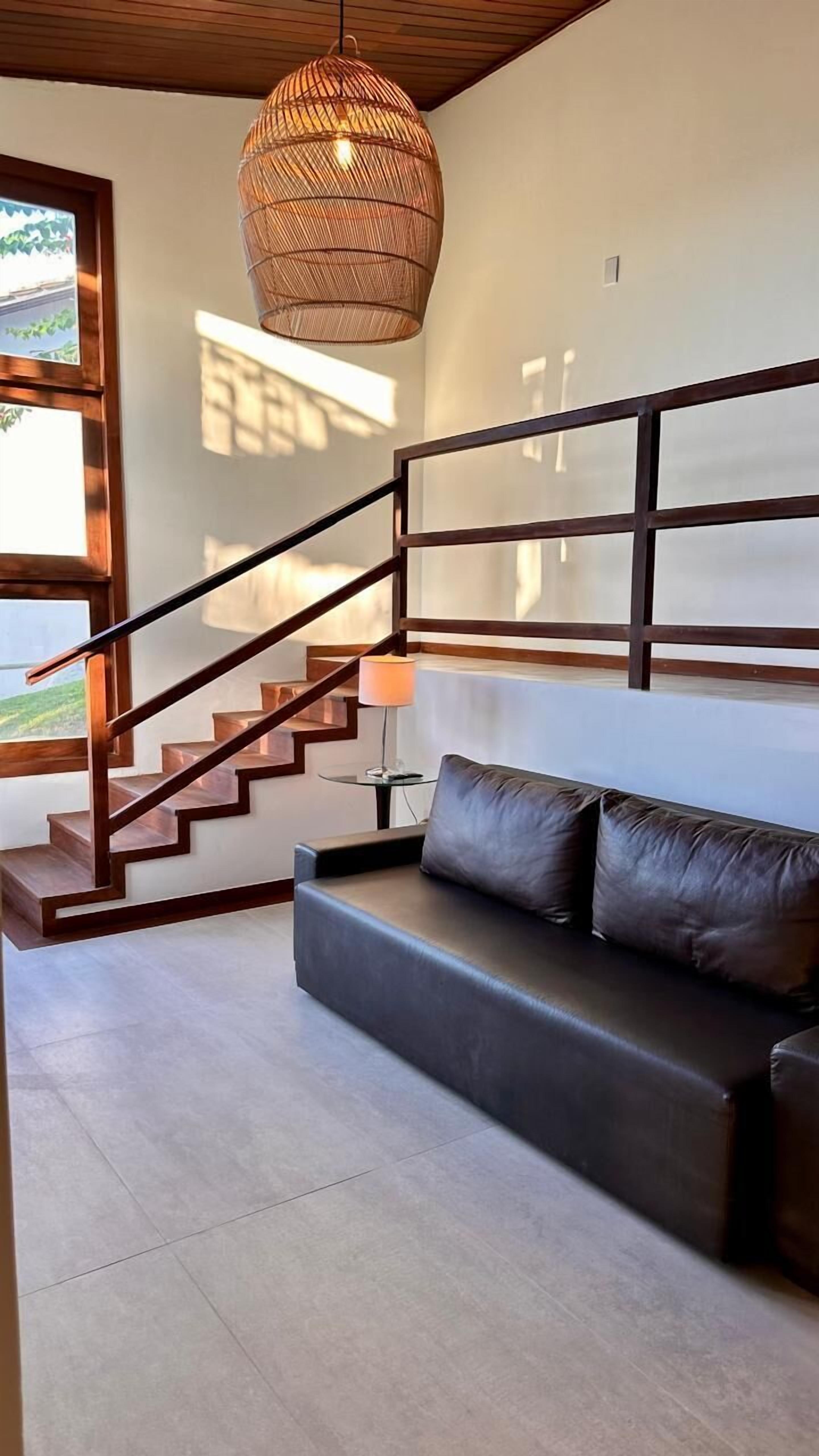 A modern interior with a staircase, a sofa, and a hanging light fixture.