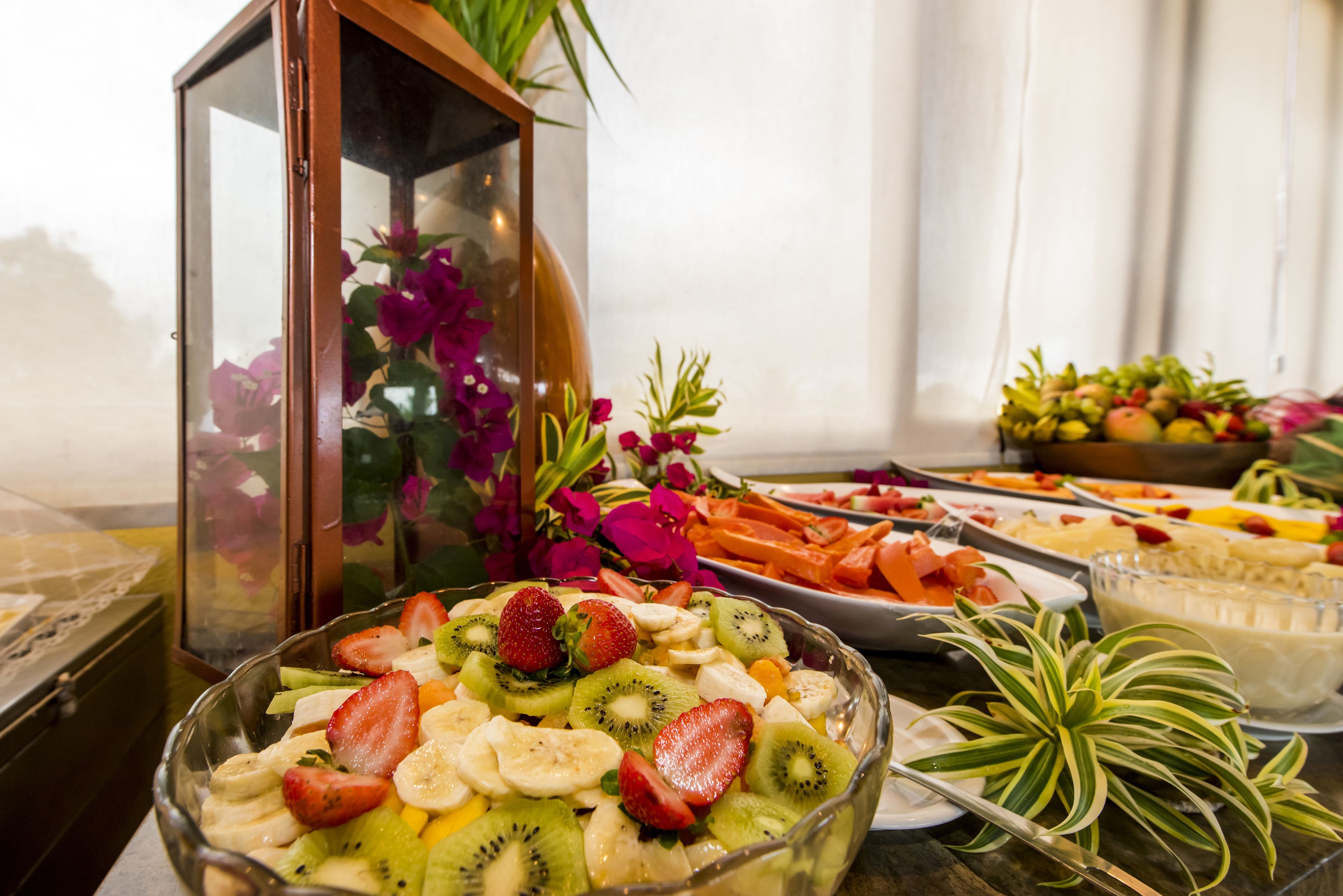 A buffet table with various food items, including a fruit salad with strawberries and kiwi, and other dishes in the background.