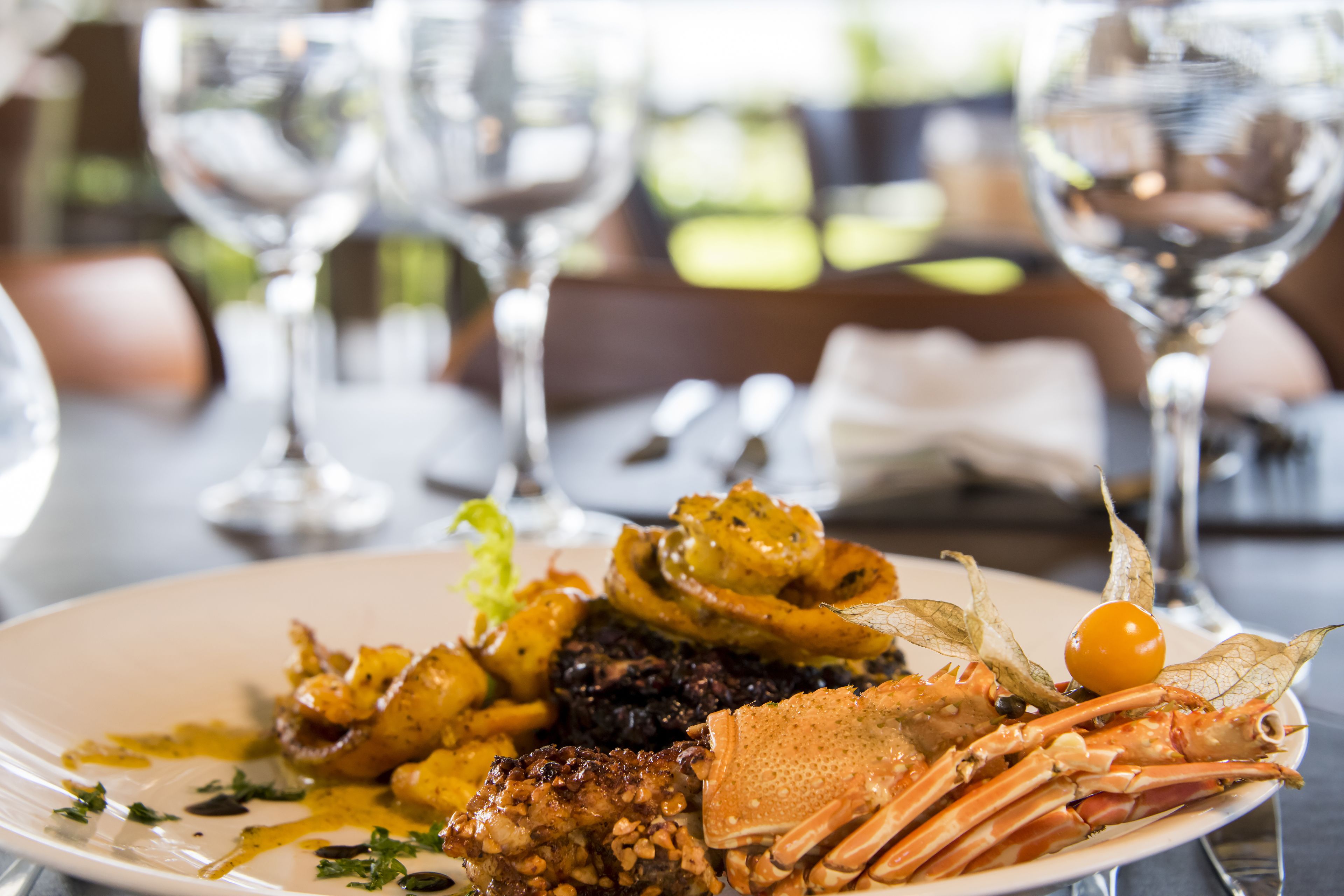 A plate of seafood with various garnishes and sauces, accompanied by wine glasses and a napkin on a table.