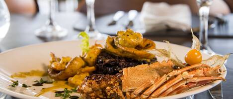A plate of seafood with various garnishes and sauces, accompanied by wine glasses and a napkin on a table.