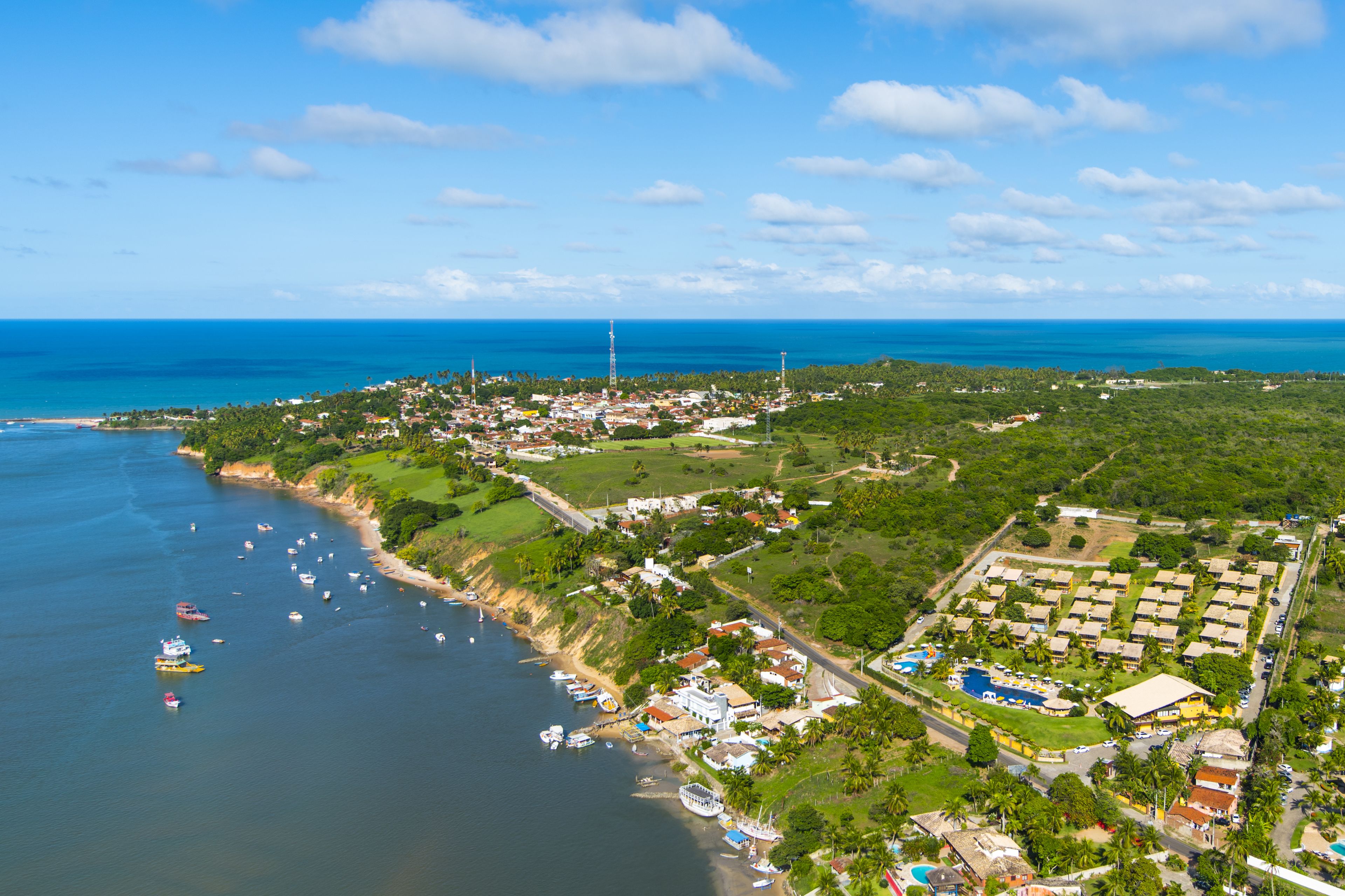 An aerial view of a coastal town with a marina, residential areas, and a large hotel complex.