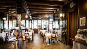Un restaurant avec des poutres en bois, un sol en briques et des tables dressées pour le repas.