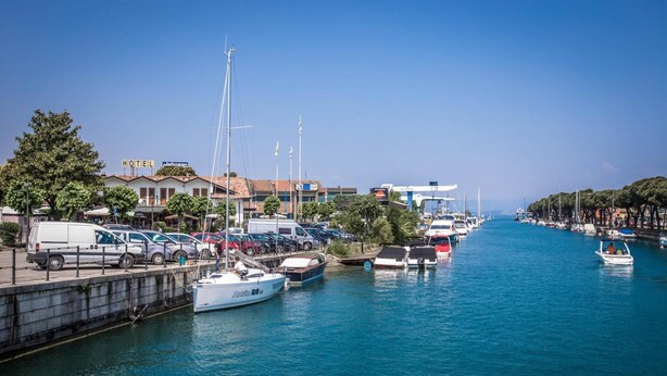 Un port de plaisance avec des bateaux amarrés, un hôtel et un ciel d’un bleu limpide.