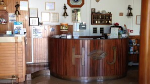 Un espace d’accueil avec un comptoir en bois, une horloge murale et divers certificats encadrés.