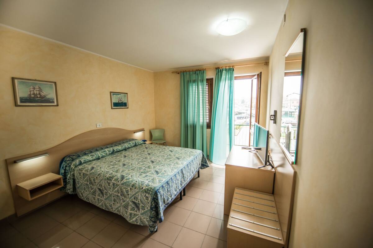 Une chambre à coucher avec un lit, une chaise, un bureau et une fenêtre avec des rideaux.