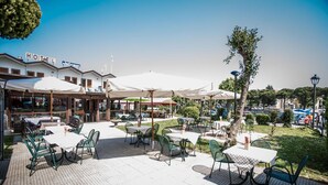 Un espace extérieur aménagé en terrasse avec des tables et des chaises, une enseigne indiquant un hôtel, et une vue sur les environs.