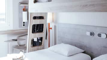 Una habitación de hotel moderna con literas, un escritorio y una silla, y una ventana.