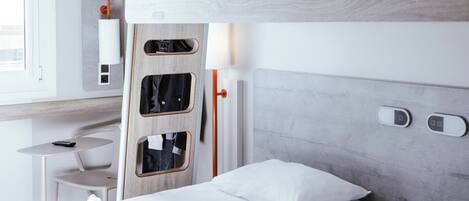 Una habitación de hotel moderna con literas, un escritorio y una silla, y una ventana.