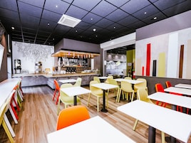 Un café moderno con zona de bar, diversas opciones de asientos y una pared decorativa.