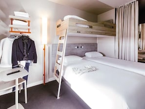 A bunk bed room with a desk, a chair, and a hanging coat rack.