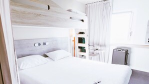 A modern hotel room with a large bed, a bedside table, a desk, and a chair. - ibis budget Luxembourg Aéroport (Niederanven)