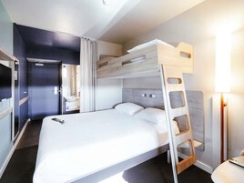 A bunk bed with a ladder, a bedside table, and a lamp.