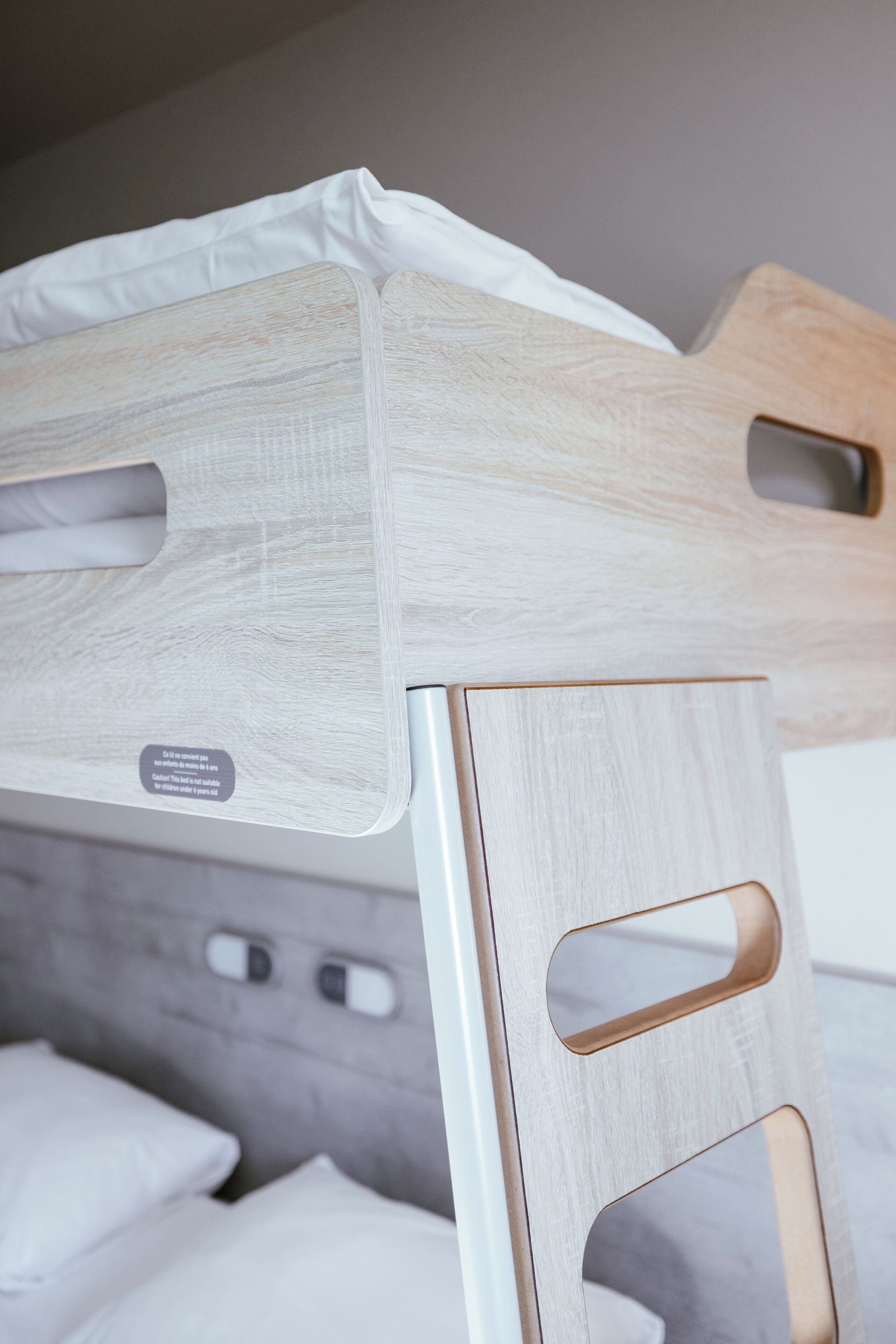 A bunk bed with a wooden headboard and a white mattress.