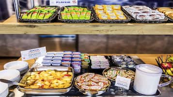Un buffet proposant divers plats et une pancarte indiquant qu’un office religieux aura lieu le matin.