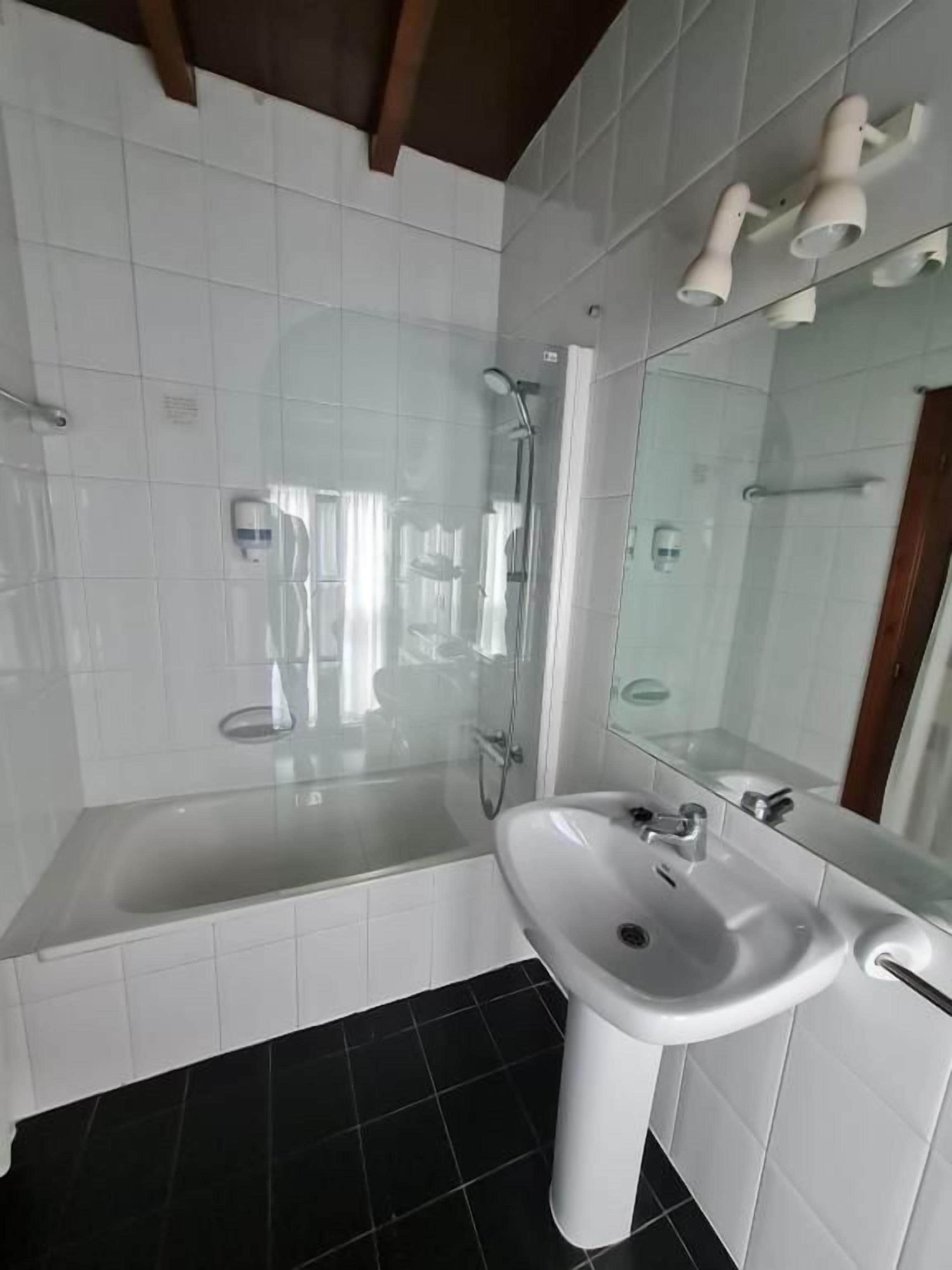 A bathroom with a glass-enclosed shower, a white sink, and a large mirror.
