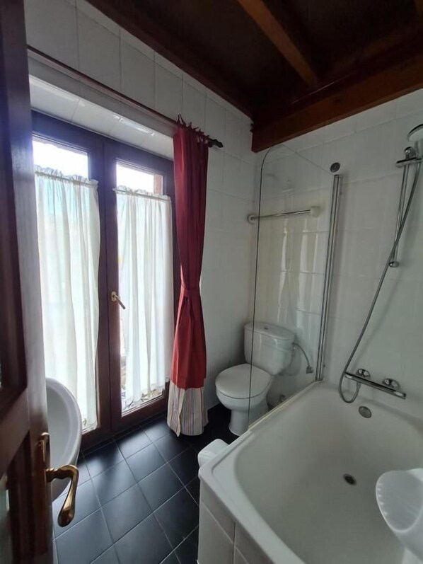A bathroom with a bathtub, toilet, and shower.