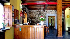 A rustic kitchen with wooden cabinets, a stone wall, and a wooden bar counter. - La Balsa (Cangas de Onis)