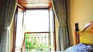 A room with a bed, a window with curtains, and a view of greenery outside. - La Balsa (Cangas de Onis)