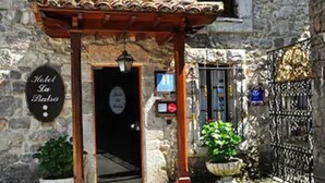 A stone building with a wooden entrance canopy, a sign reading "Hotel La Balsa," and a metal gate. - La Balsa (Cangas de Onis)